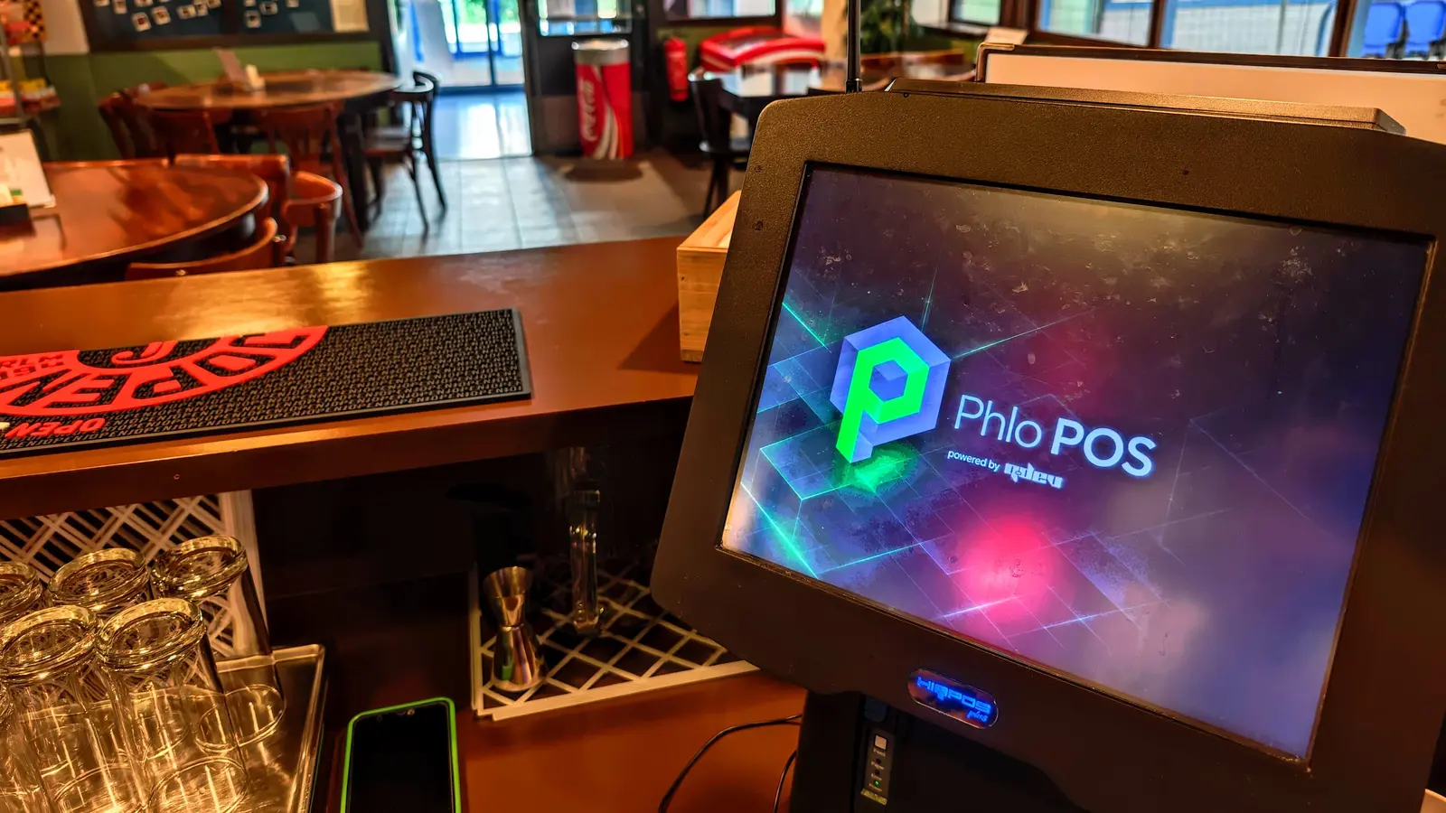 A Phlo POS till on the counter of a bar, running on the venue's own touchscreen terminal